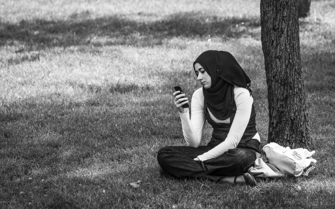 moslims zit in het gras en kijkt op haar telefoon