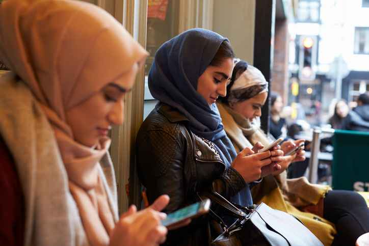 vrouwen met hoofddoek zijn bezig met hun mobiele telefoon.