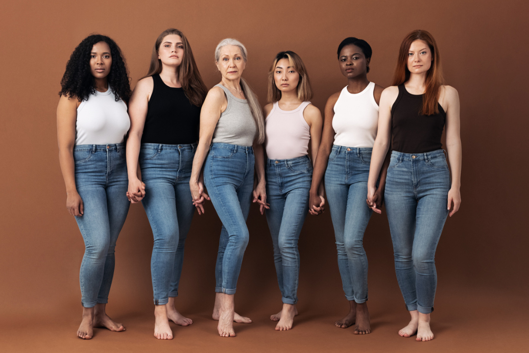 Een groep vrouwen staan voor een doek en kijken serieus in de camera.