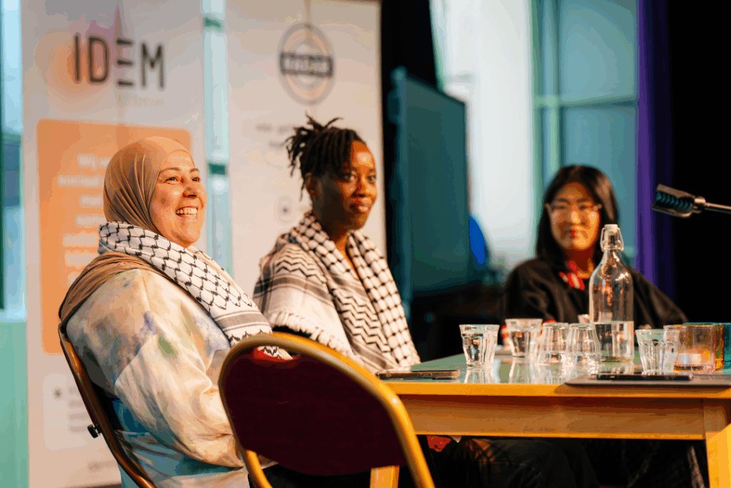 Drie panelleden Maud Mahyou, Michantely de Jong en Rui Jun Luong zitten aan tafel en kijken naar het publiek.